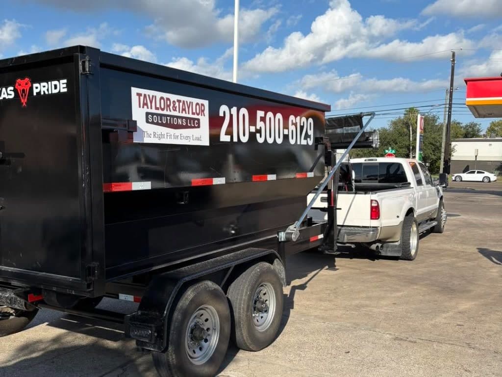 White dually truck towing Taylor & Taylor branded dumpster